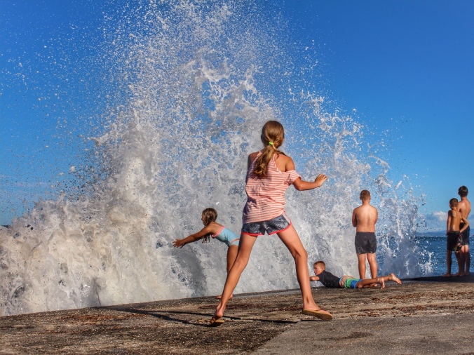 Children playing the waves breaking over seawall. Milford Beach, Auckland, NZ. Image: Su Leslie, 2016