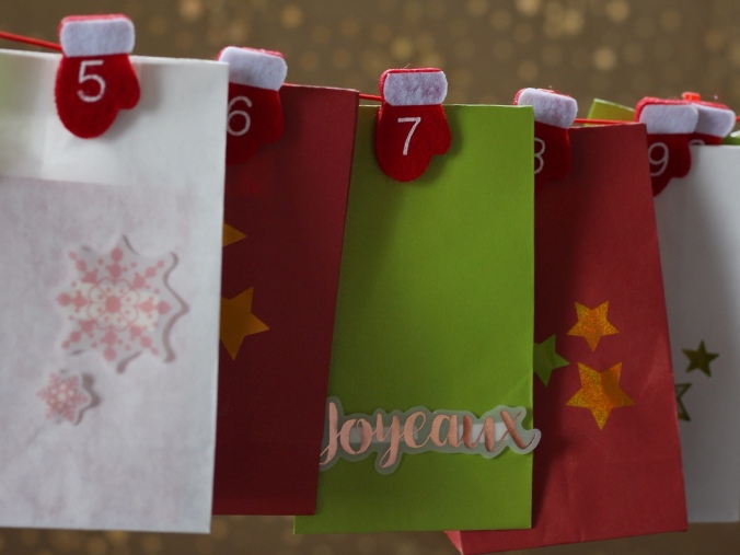Close up shot of white, red and green bags, decorated for Christmas and hung from numbered pegs. Part of an Advent Calendar. Image: Su Leslie, 2017