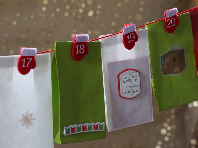 Close up colour shot of Christmas-themed bags hanging from numbered pegs, forming part of a home-made Advent Calendar. Image: Su Leslie, 2017
