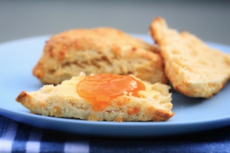 Close up shot of cut scone, and whole scone. Cut scone is buttered and has lemon thyme infused apricot jam drizzled on. Image: Su Leslie, 2018